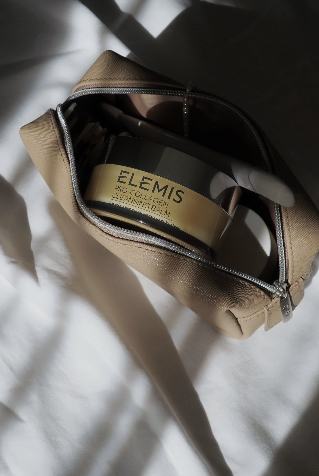 Balsam Elemis w kosmetyczce na tle światła i cieni
