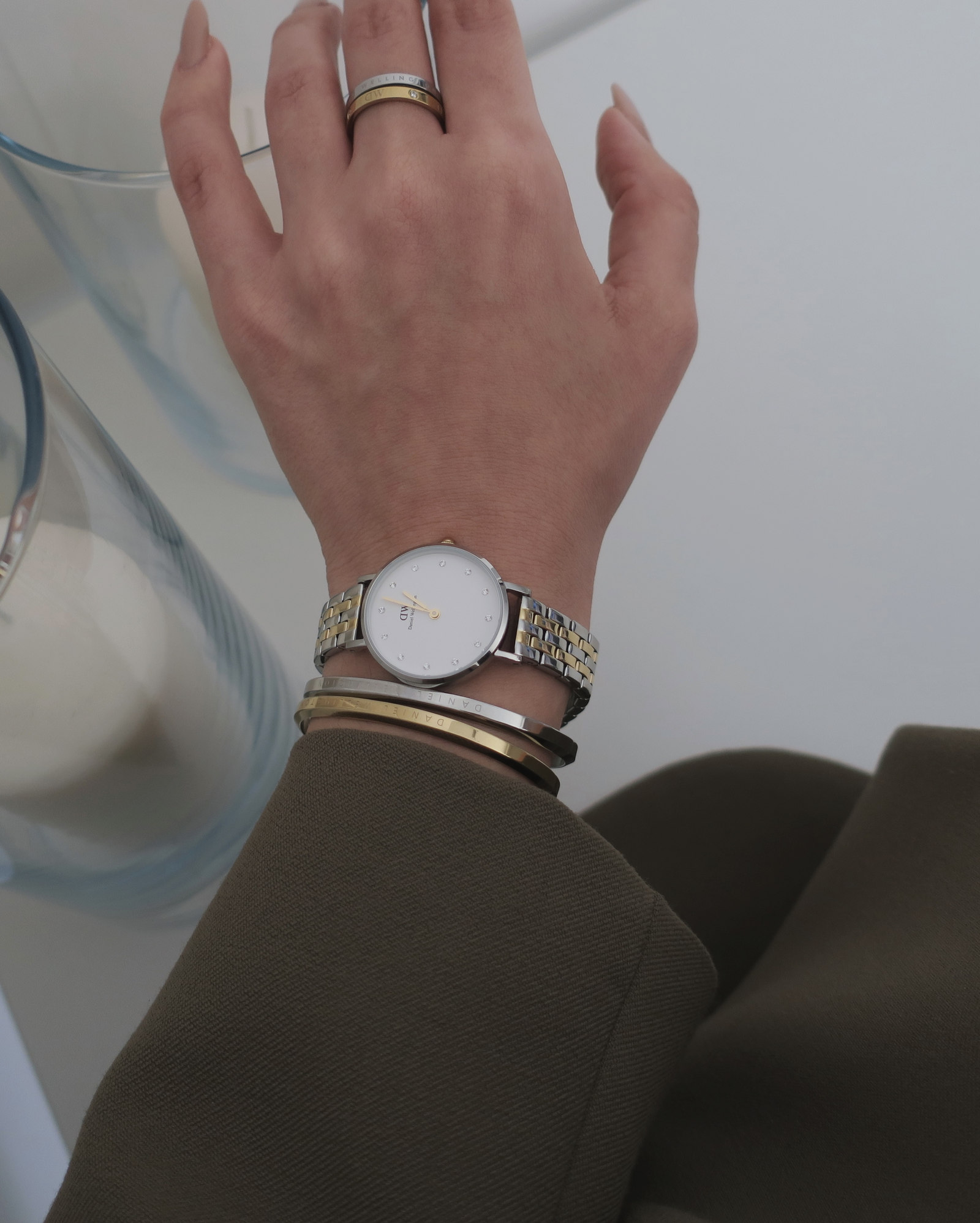 Zegarek Daniel Wellington i bransoletki przy zielonej marynarce